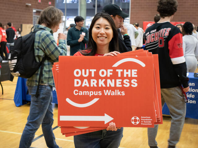 A person smiling with a cardboard sign in their hands