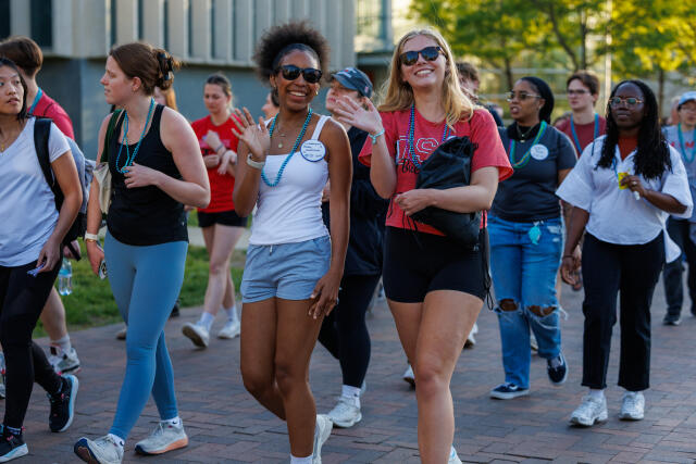 Two women smiling at camera while walking outside during the out of the darkness campus walk
